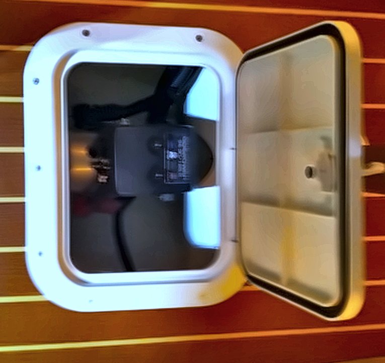 Thruster motor under a teak service hatch in the forward cabin sole
